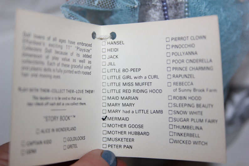 May include: A white card with a checklist of various characters, including Hansal, Heidi, Jack, Jill, Little Bo-Peep, Little Girl with a Curl, Little Miss Muffet, Little Red Riding Hood, Maid Marian, Mary Mary, Mary had a Little Lamb, Mermaid, Mother Goose, Mother Hubbard, Musketeer, Peter Pan, Pierrot Clown, Pinocchio, Pollyanna, Poor Cinderella, Prince Charming, Rapunzel, Rebecca of Sunny Brook Farm, Robin Hood, Sleeping Beauty, Snow White, Sugar Plum Fairy, Thumbelina, Tinkerbell, and Wicked Witch. The card also includes a section for "Story Book" with a checklist of Alice in Wonderland, Captain Kidd, Goldilocks, and Gretel.