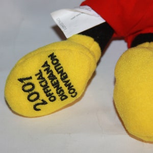 Puede incluir: Guante de Mickey Mouse de felpa amarillo con bordado negro que dice "2001 Convenci&oacute;n Oficial de Disneyana".
