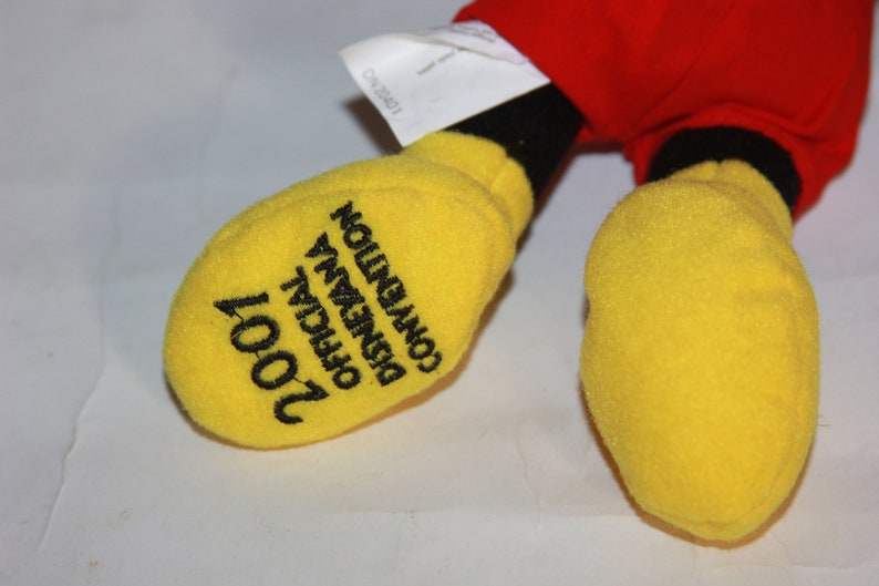 Puede incluir: Guante de Mickey Mouse de felpa amarillo con bordado negro que dice "2001 Convenci&oacute;n Oficial de Disneyana".
