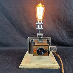 Lámpara decorativa única de diseño ecológico con reciclaje de cámara Polaroid y bombilla decorativa vintage para regalo de fotógrafo. Envío mediante cartón reciclado.