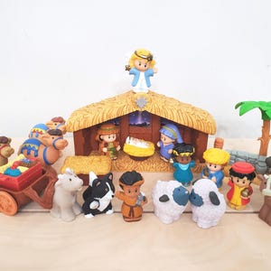 May include: A colorful nativity scene playset featuring a stable, angel, and various figures including the three wise men, animals, and baby Jesus. The figures are made of plastic and are brightly colored.