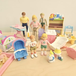 May include: A collection of plastic dollhouse furniture and figures including a bed, a cradle, a high chair, a stroller, a sink, a changing table, an ironing board, and several small human figures and a cat figure in various colors.