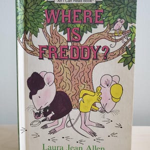 May include: A children's book cover with a green tree and two pink mice. The title of the book is "Where is Freddy?" and the author is "Laura Jean Allen".