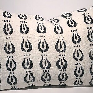 Puede incluir: Almohada blanca con un patrón floral negro. La almohada es rectangular y tiene un diseño simple.