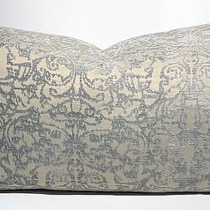 Puede incluir: Una almohada decorativa con un diseño estampado en gris claro y blanco. El patrón presenta un motivo floral repetitivo.