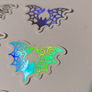 Nietoperze Halloween z otwartymi, szczegółowymi skrzydłami, naklejki foliowe, zestaw 6 sztuk, dostępne w różnych kolorach, wydrukowane na przezroczystym papierze samoprzylepnym.
