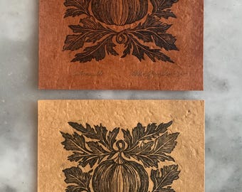 May include: Two prints of a black and white illustration of a pumpkin with leaves on a brown and beige background. The bottom print has the text "Autumnville" and "Alison Gauci - 2021".