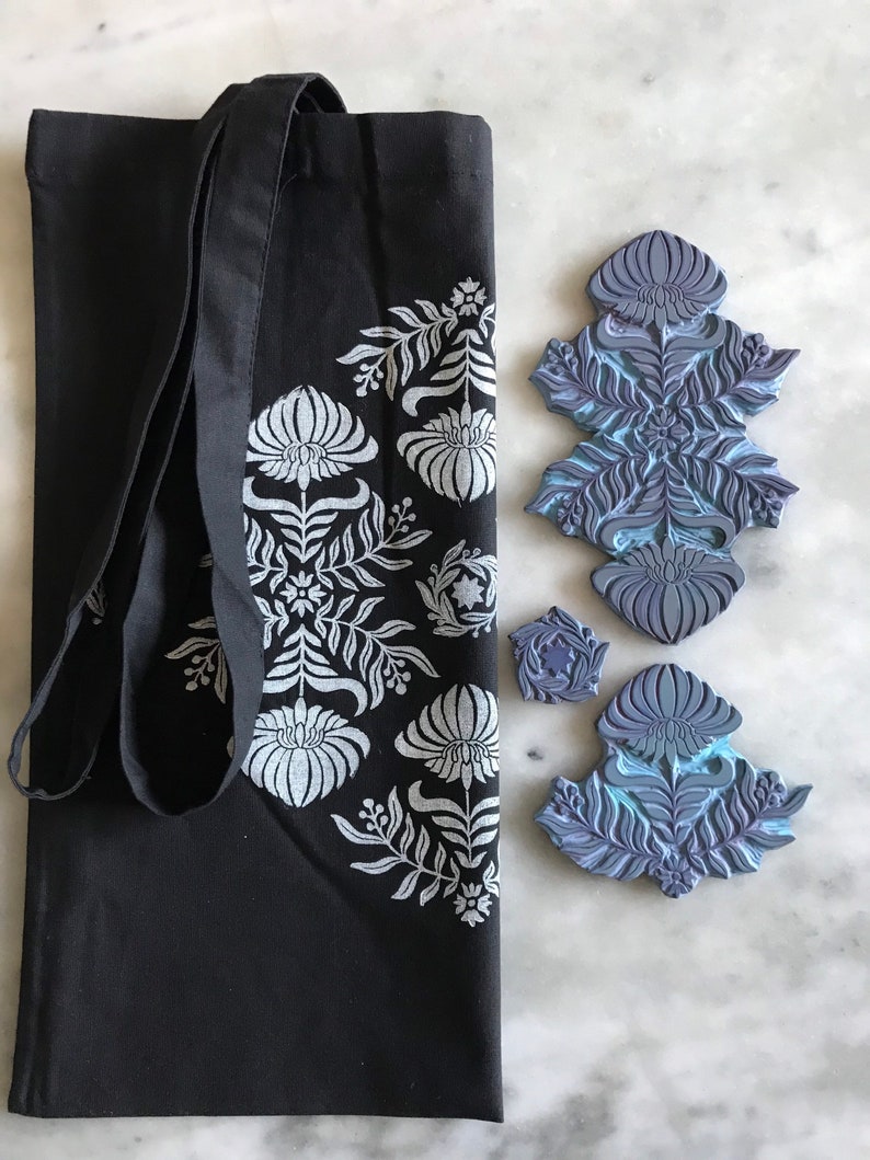 May include: A black tote bag with a white floral design. Three blue rubber stamps with floral designs are also shown.