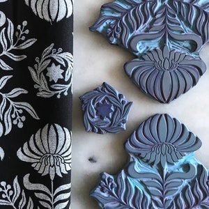 May include: Four blue and purple rubber stamps with floral and leaf designs. The stamps are on a white marble surface.