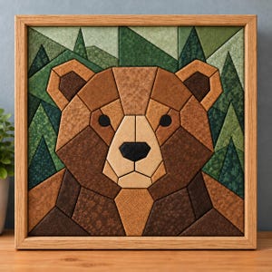May include: A square framed wall art piece featuring a geometric bear portrait composed of various brown fabric patches. The background consists of triangular green fabric segments representing a forest of pine trees. The frame is light wood.