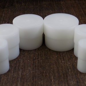 May include: Set of six white plastic round bottle stoppers of varying sizes.
