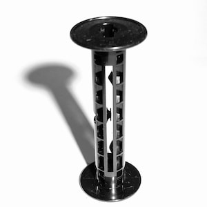 Puede incluir: Carrete de revelado de película de plástico negro con un núcleo central y dos extremos circulares.