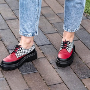 May include: Red and black checkered pattern leather shoes with black laces. The shoes have a thick black platform sole.