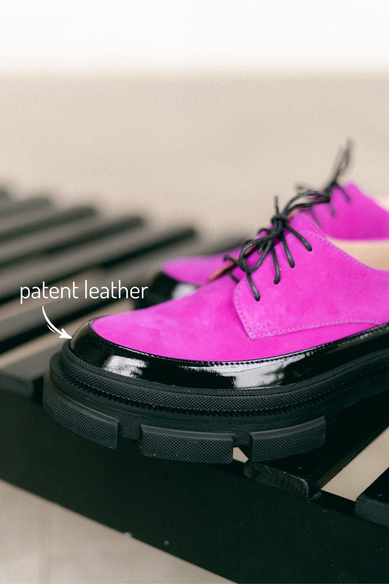 A pair of black and pink leather shoes with black laces and a platform black sole.