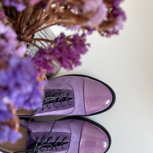 May include: A pair of purple leather lace-up shoes with a patent leather toe cap.