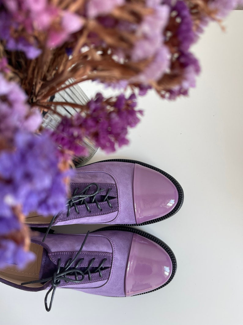 May include: A pair of purple leather lace-up shoes with a patent leather toe cap.