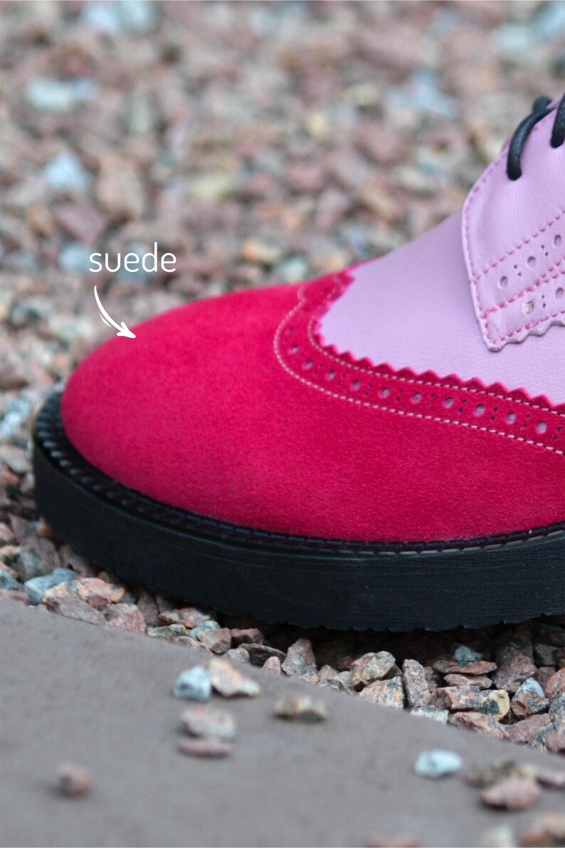 Pu&ograve; includere: Primo piano di una scarpa da donna rosa e rossa con punta in camoscio e suola nera. La parola "suede" &egrave; scritta sull'immagine.