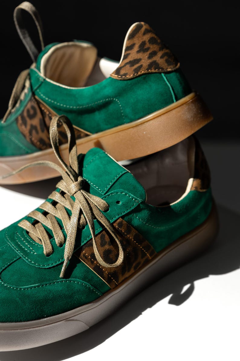 Green suede sneakers with brown leopard print accents. The sneakers have green laces and a brown sole.