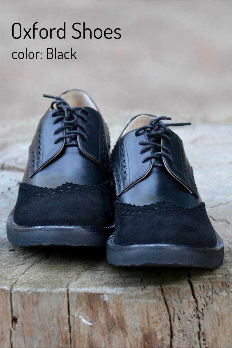 Pu&ograve; includere: Un paio di scarpe Oxford in pelle nera con punta in camoscio e chiusura con lacci. Le scarpe hanno un design brogue e una suola spessa in gomma.