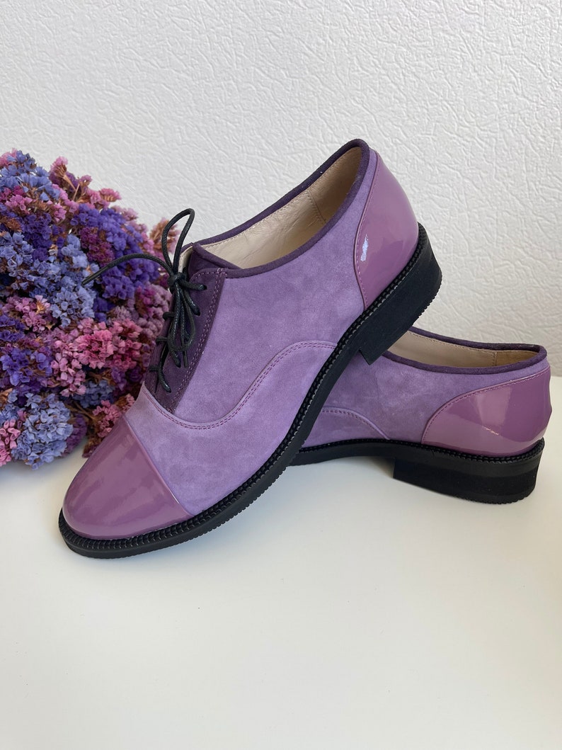 May include: Purple suede and patent leather lace-up shoes with a rounded toe. The shoes have a black rubber sole.