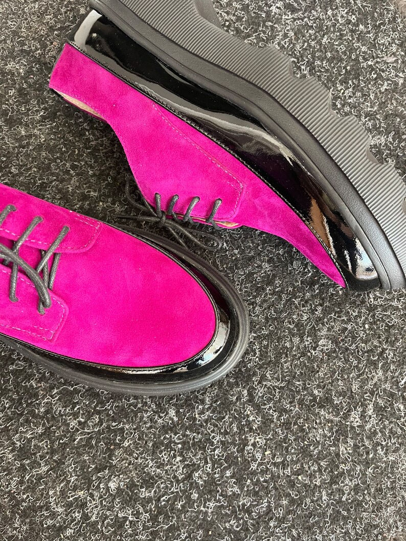 May include: A pair of fuchsia suede shoes with black patent leather trim and a chunky black platform sole.