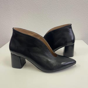Könnte beinhalten: Schwarze Leder-Stiefeletten mit spitzer Zehenpartie und Blockabsatz.