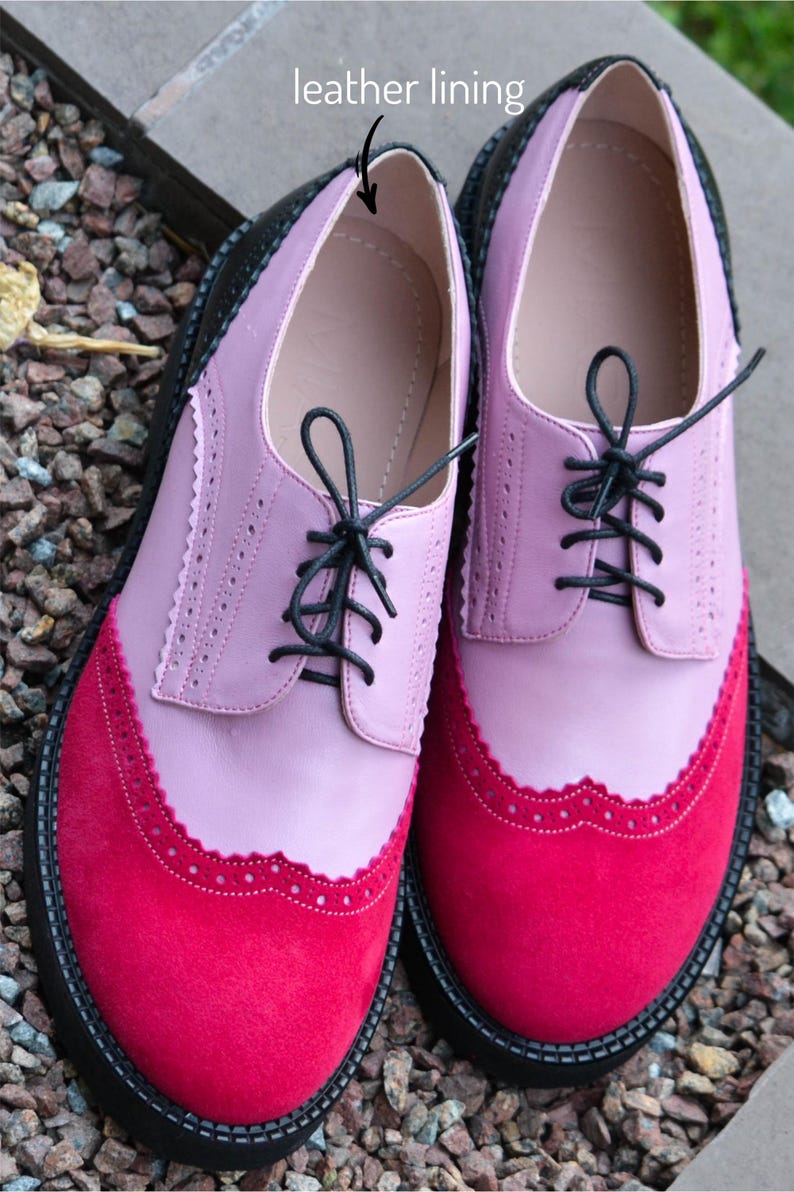 Pu&ograve; includere: Un paio di scarpe in pelle rosa e rosse con lacci neri e suola in gomma nera. Le scarpe hanno un bordo a festoni e una fodera in pelle.