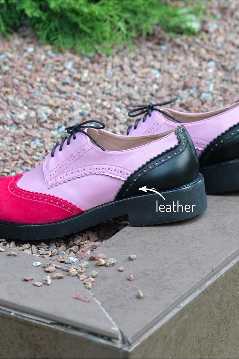 Pu&ograve; includere: Un paio di scarpe Oxford in pelle rosa, nera e rossa con chiusura a lacci. Le scarpe hanno una suola in gomma nera e una fodera in pelle bianca. La parola "pelle" &egrave; scritta sulla suola della scarpa.