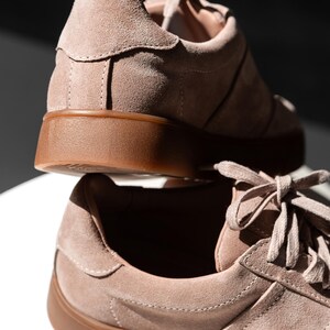 May include: A pair of light brown suede sneakers with a gum sole. The sneakers have a lace-up closure and a classic design.