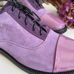 May include: Purple suede and patent leather lace-up shoes with a rounded toe.