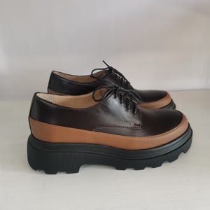 May include: Brown leather lace-up shoes with a chunky black platform sole.