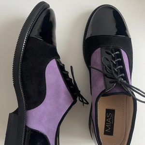 May include: A pair of black and purple leather lace-up shoes with a black patent leather toe cap. The shoes have a black rubber sole and are made by the brand MIAS.