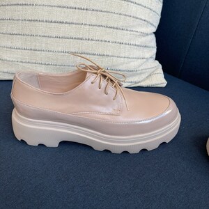 May include: A pair of light brown leather lace-up shoes with a chunky platform sole.