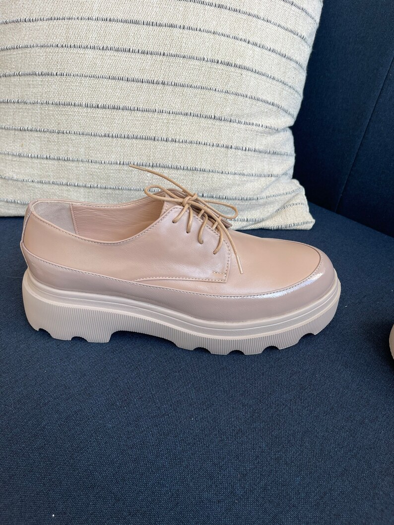 May include: A pair of light brown leather lace-up shoes with a chunky platform sole.