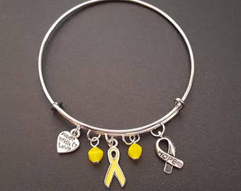 May include: Silver bangle bracelet with yellow ribbon charms, a heart charm with the words "Mom Will Love This", and a ribbon charm with the word "HOPE".