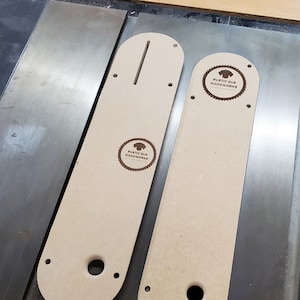 May include: Two beige wooden router templates with cutouts for a router bit and a slot for a guide. The templates have the text "Rustic Gus Woodworks" on them.