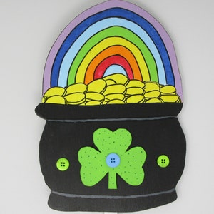 May include: A black pot of gold with a rainbow on top. The pot has a green shamrock and three green buttons on the front.