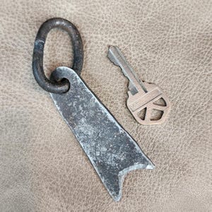 May include: A silver key with a black metal loop attached to a silver metal key chain. The key has the number "99" engraved on it.