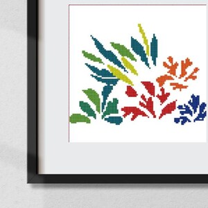 May include: A cross-stitch pattern featuring a colourful abstract design of stylised leaves and flowers in shades of green, blue, red, orange, and yellow. The pattern is framed in a black frame.