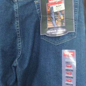 Puede incluir: Un par de pantalones vaqueros azules de mezclilla con una etiqueta de Wrangler. La etiqueta dice "Real. Comfortable. Jeans." y "Stretch Jeans, Extra Comfort". Los pantalones vaqueros son talla 38x30.