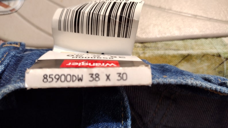 Puede incluir: Primer plano de una etiqueta de mezclilla azul con el texto "Wrangler 85900DW 38 X 30".