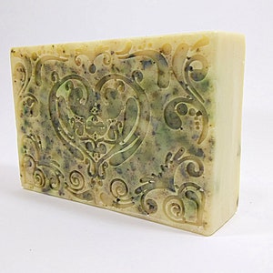 May include: A rectangular bar of soap with a green and white swirl design. The soap has a heart-shaped design in the center with intricate swirls.