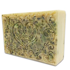 May include: A bar of soap with a heart-shaped design and a floral pattern. The soap is a light yellow color with green and brown swirls.
