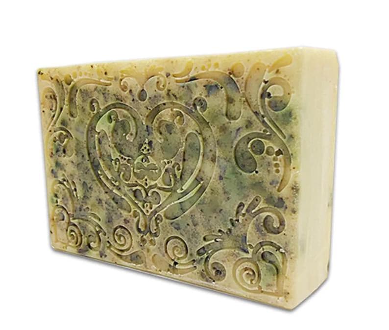 May include: A bar of soap with a heart-shaped design and a floral pattern. The soap is a light yellow color with green and brown swirls.