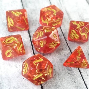 May include: Set of seven red dice with gold flecks and gold numbers. The dice are a d4, d6, d8, d10, d%, d12, and d20.