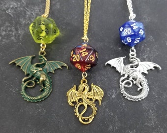 May include: Three fantasy-themed necklaces. Each features a different colored 20-sided die pendant, with a dragon charm. The dice are green, red, and blue. The dragon charms are green, gold, and silver, suspended from gold and silver chains.
