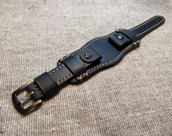 May include: Black leather watch strap with a buckle fastening and contrasting white stitching detail. The strap is designed to fit around the wrist.