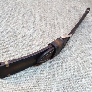 May include: A brown leather watch strap with white stitching and a silver buckle.