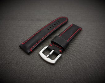 May include: Black leather watch strap with red stitching. The strap has a silver buckle.