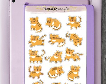 Puede incluir: Una hoja de pegatinas con 18 adorables ilustraciones de tigres naranjas en diferentes poses y expresiones. Las pegatinas están sobre un fondo blanco con el texto "PancakeBunnyCo" en la parte superior.